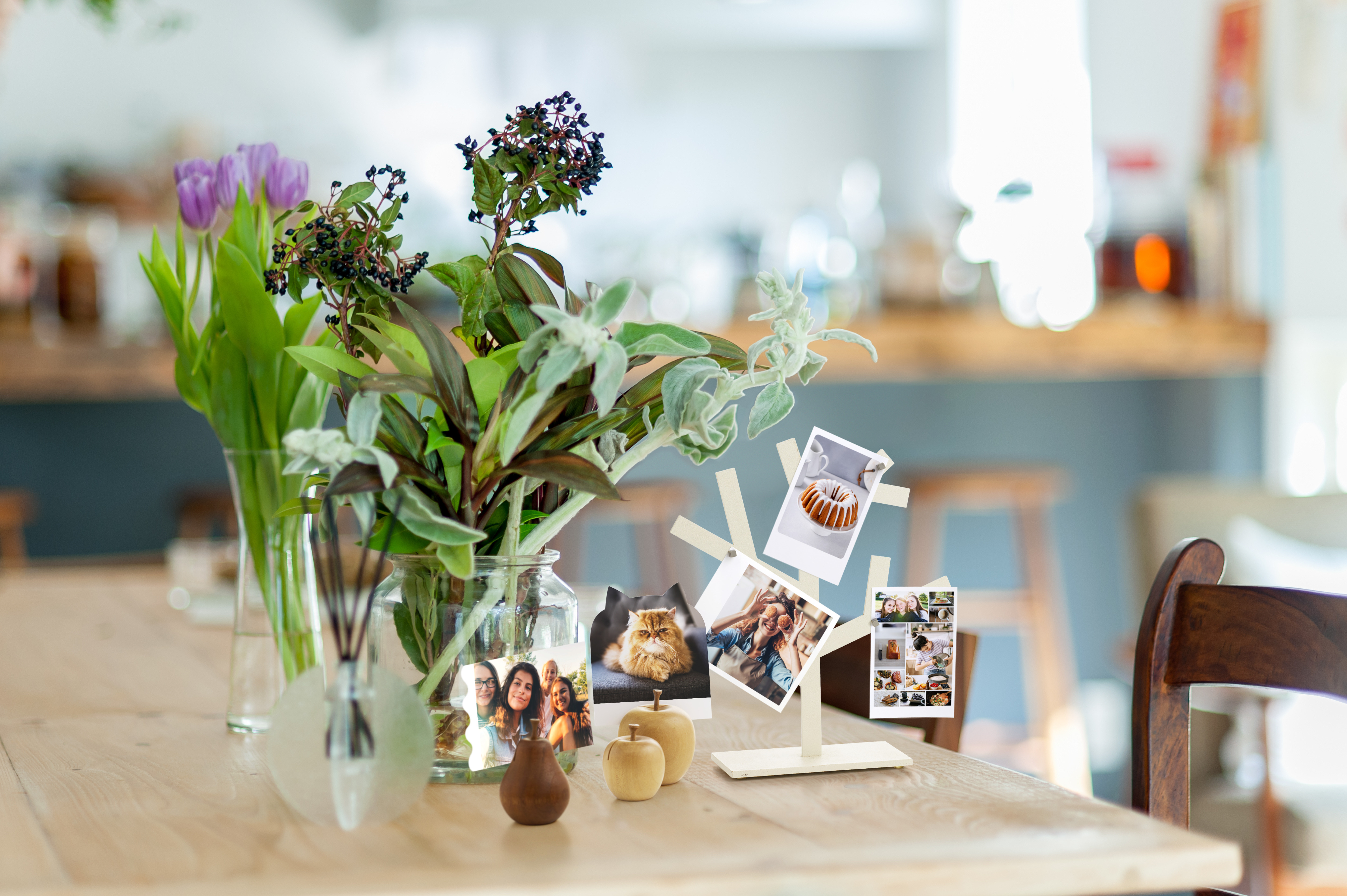 Ein Tisch mit einem Blumenbouquet, Fotohalter mit Bildern von Menschen und einem Kuchen, und Holzdekoration in einem gemütlichen Raum.