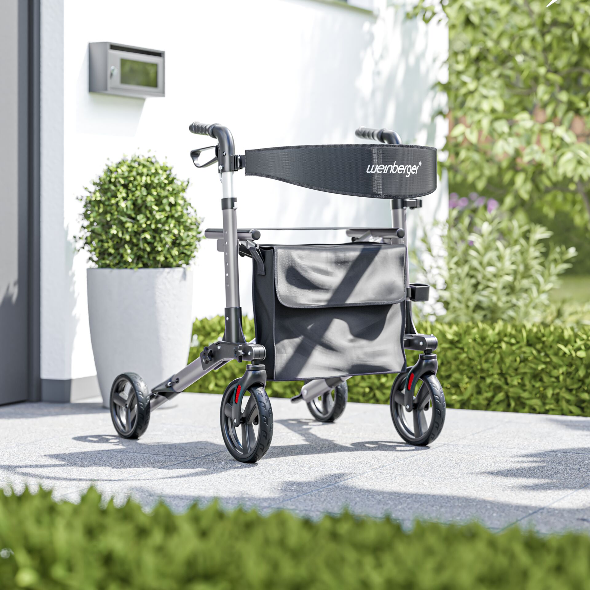 Ein moderner Rollator steht auf einer Terrasse neben grünen Pflanzen.