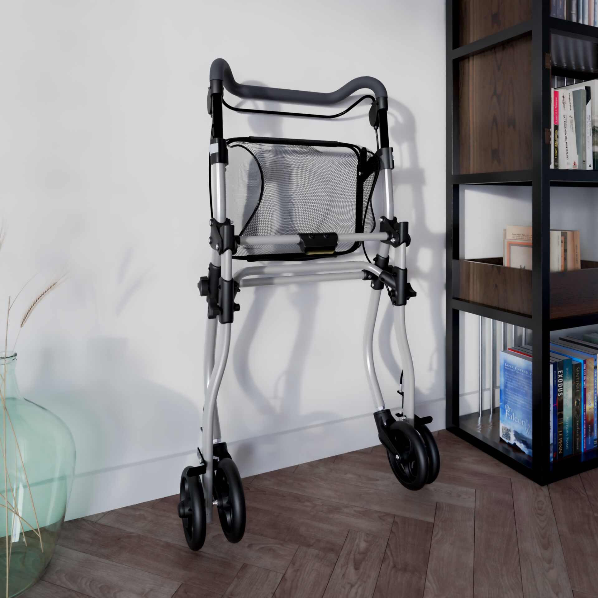 Silberner faltbarer Rollator mit schwarzem Netzkorb und Rollen, neben einem Bücherregal auf Parkettboden