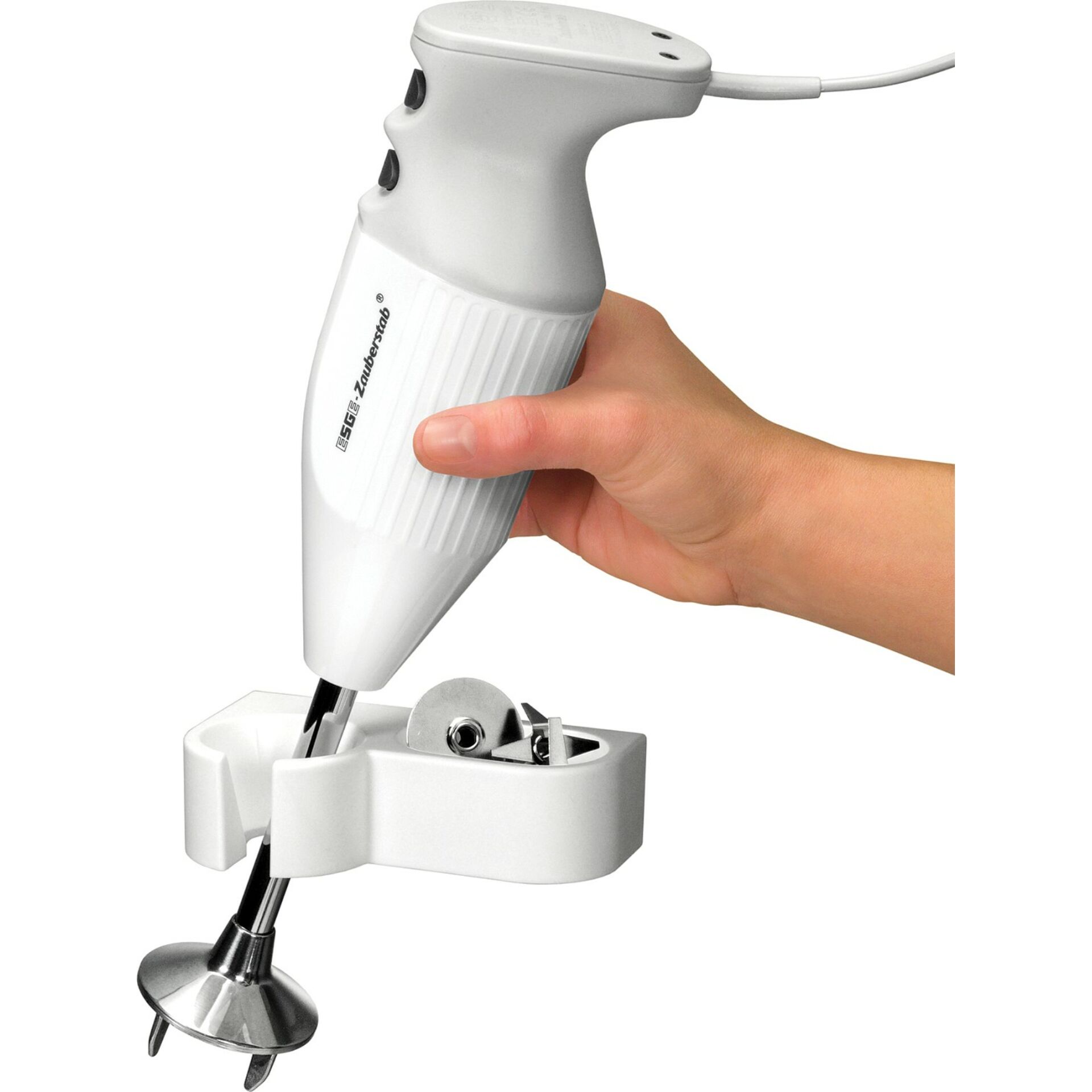 Eine Hand hält einen weißen Handmixer mit Zubehör auf einer weißen Halterung