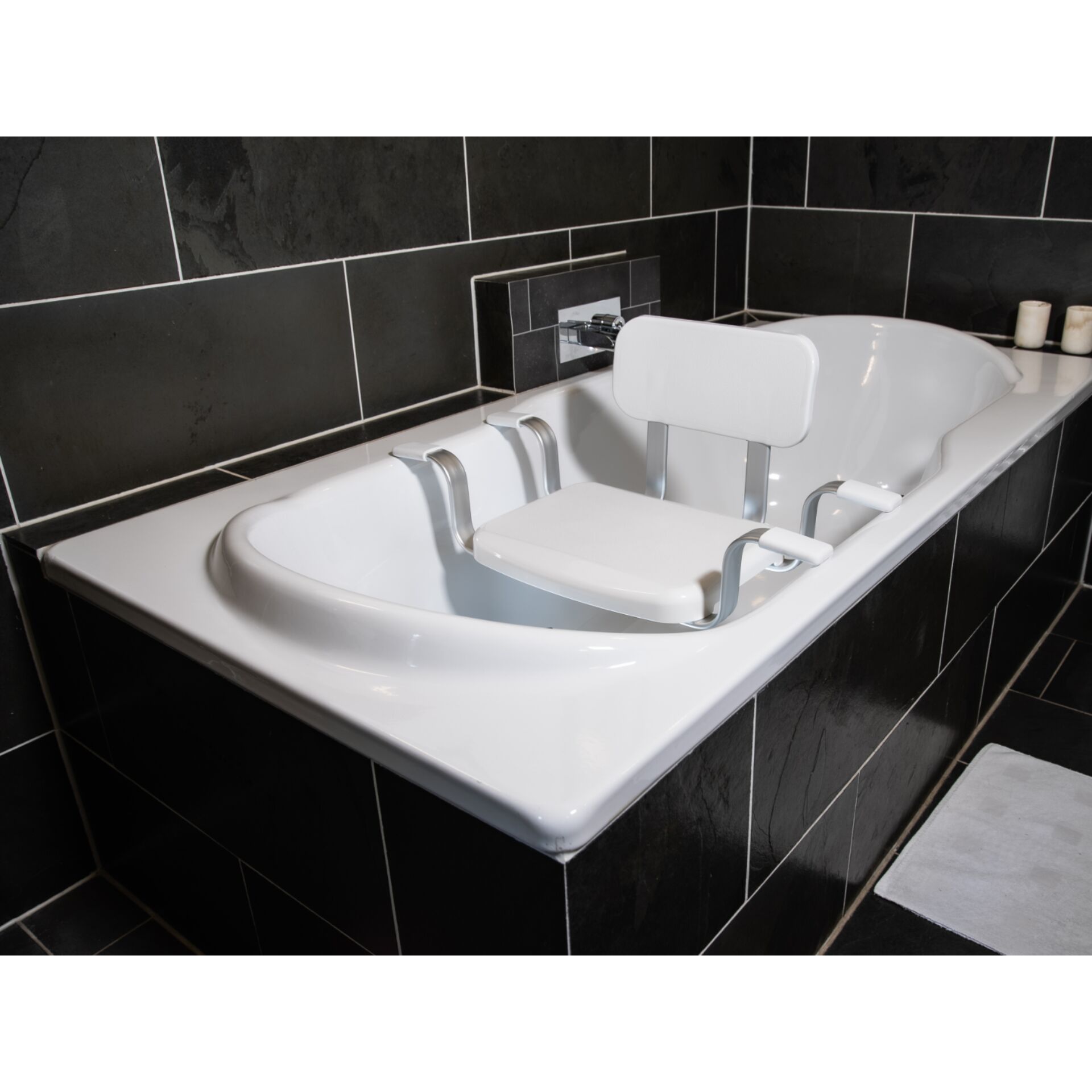 Badewannensitz in einer modernen weißen Badewanne mit schwarzer Fliesenwand