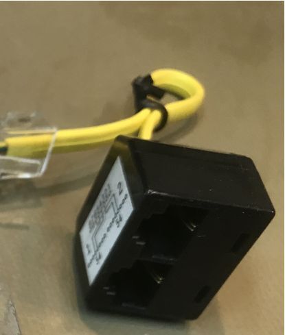 Nahaufnahme eines schwarzen Steckadapters mit gelbem Kabel auf Tisch